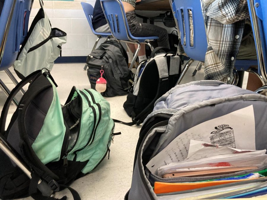 Student backpacks on the floor of a classroom could cause a trip hazard.